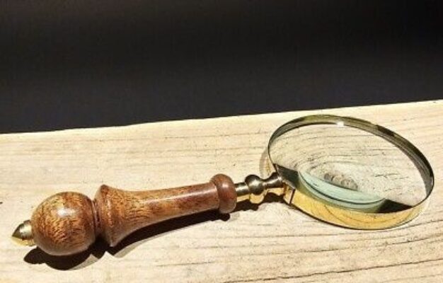 Antik förstoringslupp med trähandtag på en ljus träyta