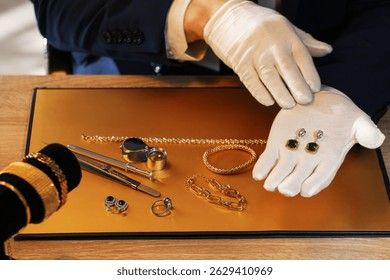 En expert med vita handskar undersöker guldsmycken inför en auktion.